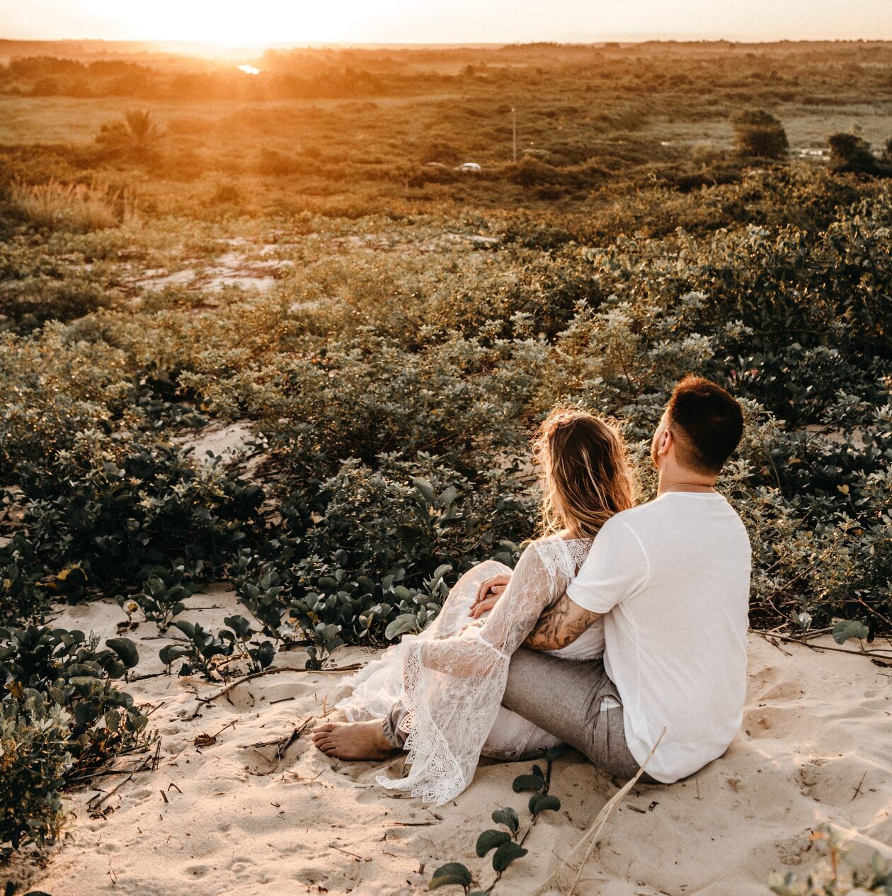 Casal abraçado na areia ao pôr do sol